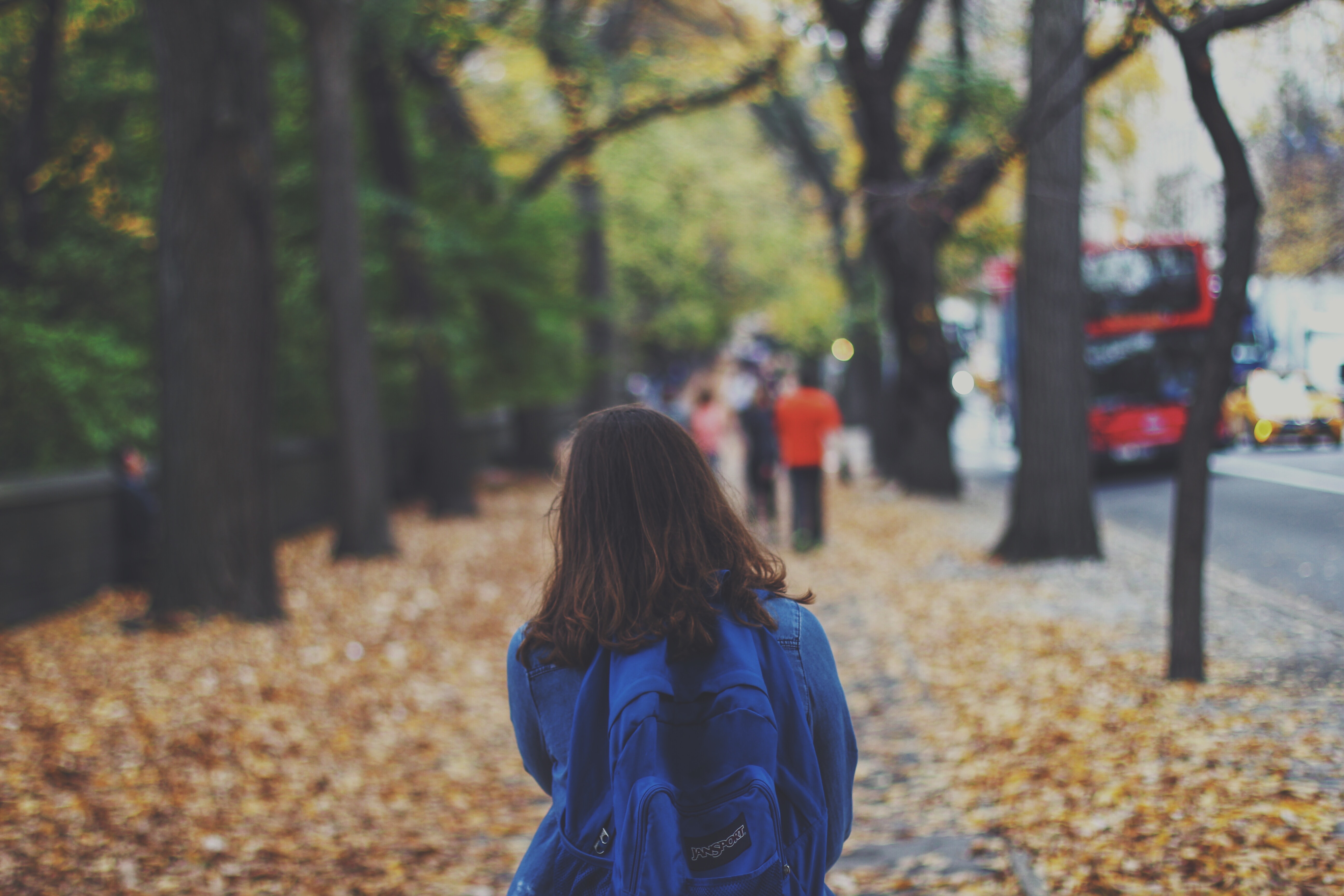 School girl walking on a sidewalk during autumn 